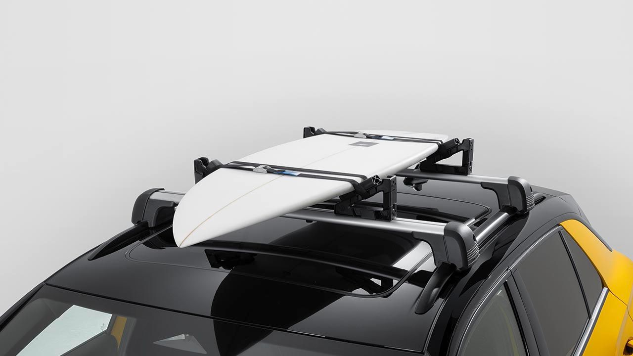 Volkswagen Dachträger mit Universalhaltern und befestigtem Surfbrett auf dem Dach eines gelben Volkswagen T-Roc.