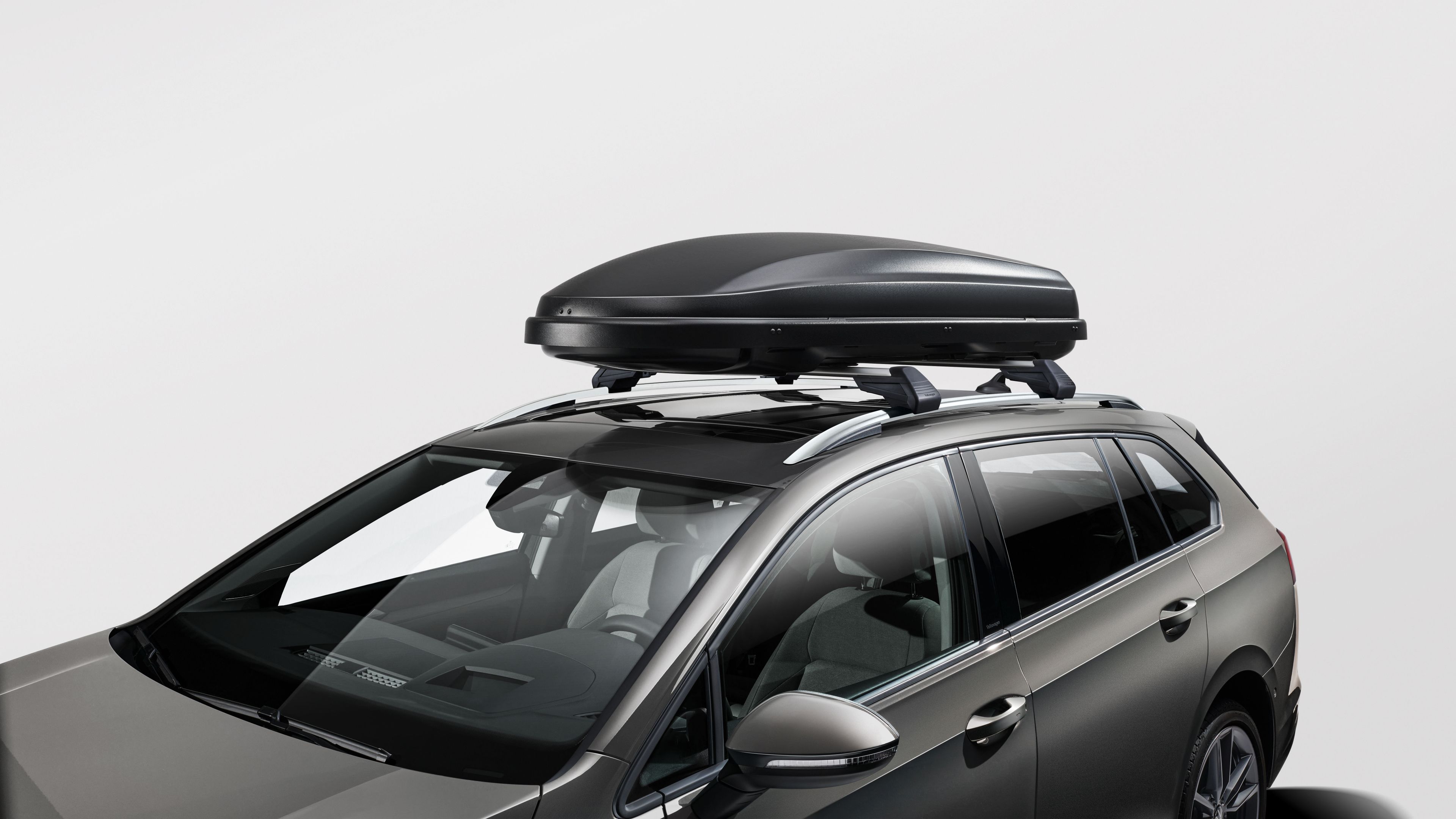 Eine schwarz matte Volkswagen Dachbox auf dem Dach eines grauen Volkswagen.