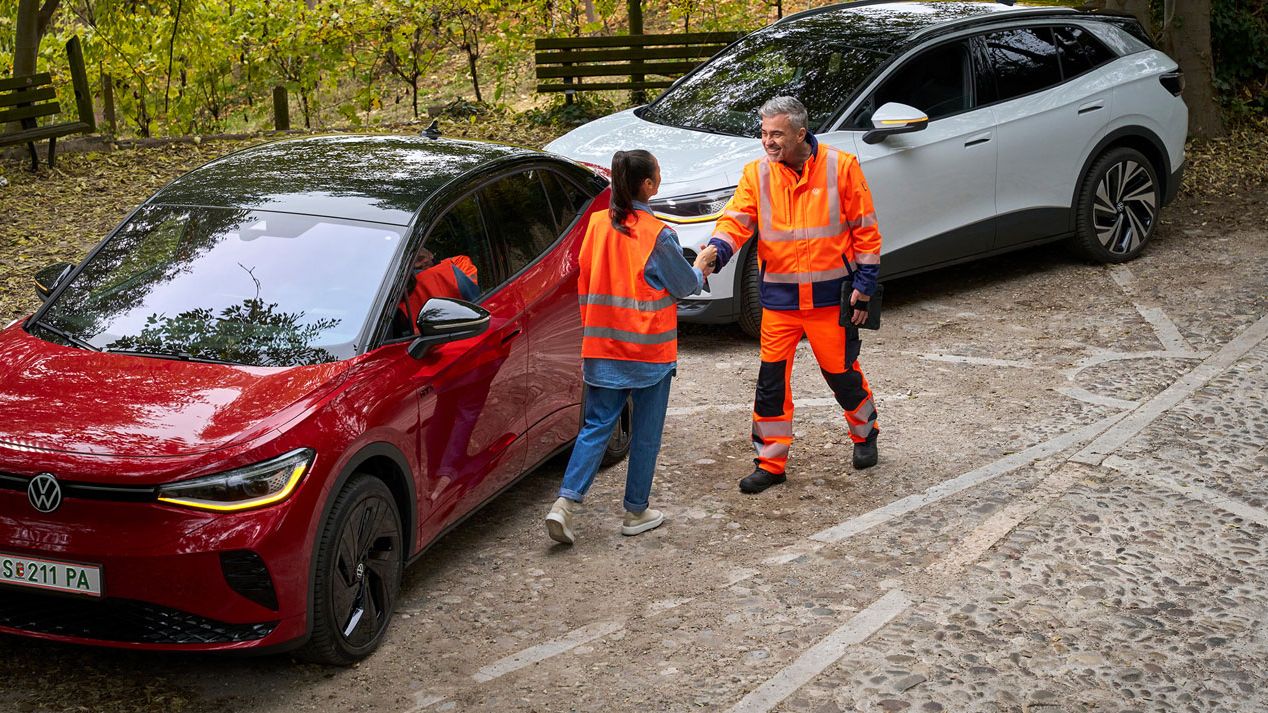 Frau mit Warnweste und Mitarbeiter der Volkswagen Pannenhilfe neben zwei VW ID. Fahrzeugen.