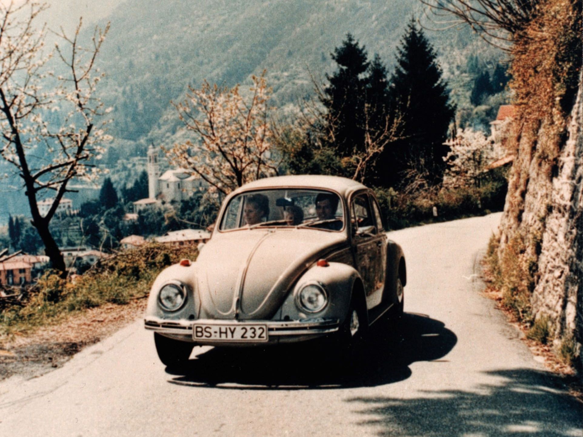 VW Käfer fährt eine Bergstraße hinauf. 