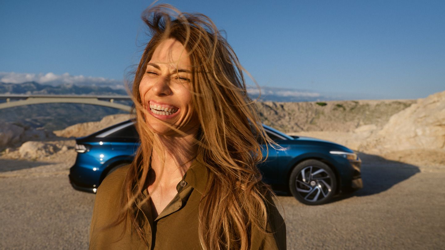 Eine Frau steht vor dem ID.7 und lacht. 