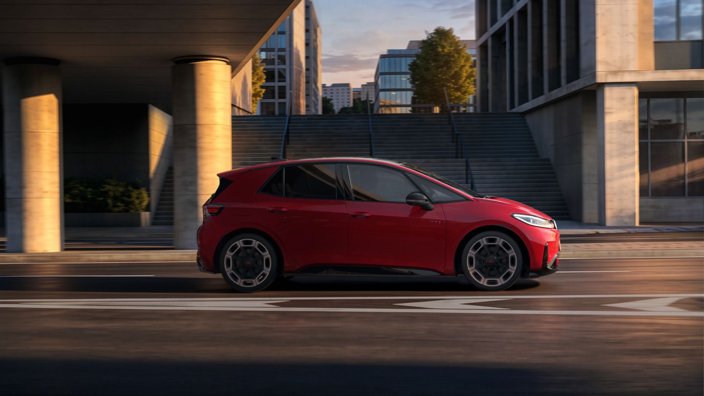 [AI-modified] – Seitenansicht eines roten VW ID.3 GTI während der Fahrt unter einer Brücke in der Stadt.