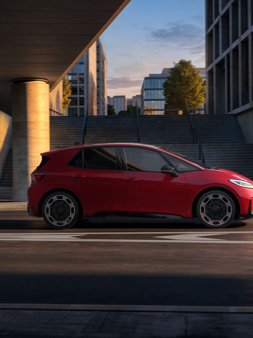 [AI-modified] – Seitenansicht eines roten VW ID.3 GTI während der Fahrt unter einer Brücke in der Stadt.