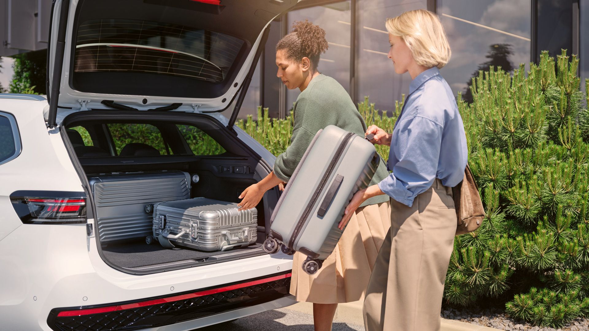 Zwei Frauen beladen den Kofferraum eines VW Passat mit Koffern