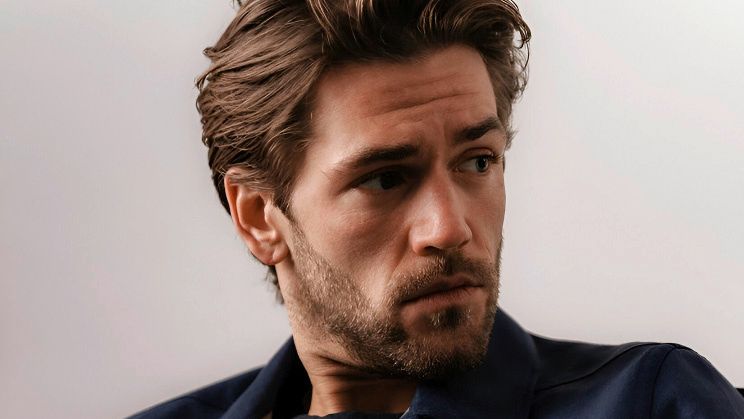 Portrait von Schauspieler Ben Dahlhaus. Er trägt schwarze und dunkelblaue Klamotten und sein Blick richtet sich von der Kamera weg.