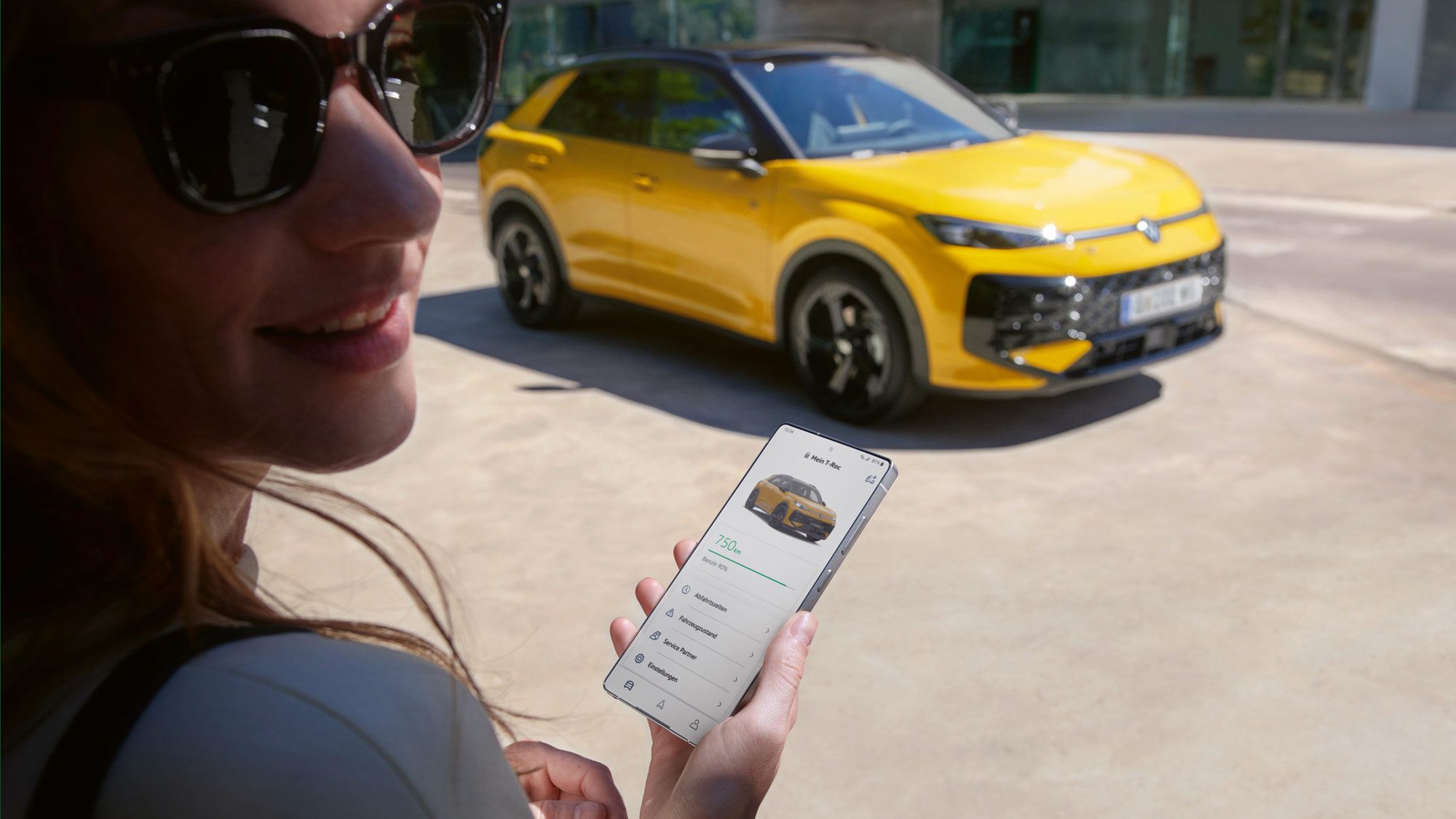 Eine Frau nutzt die App VW Connect nahe ihres VW T-Roc R-Line.