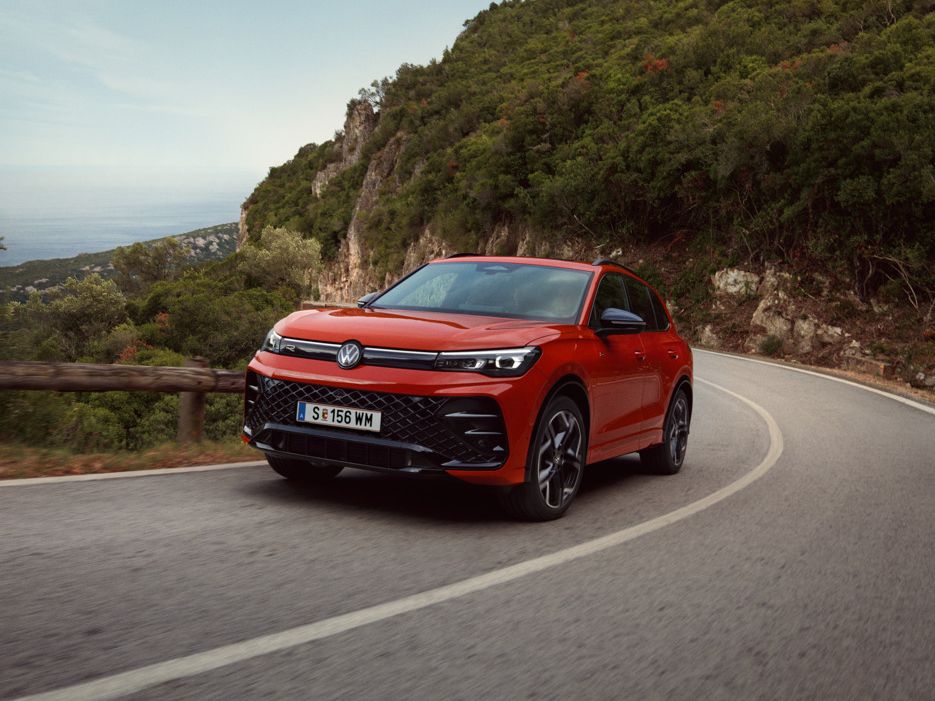 Roter VW Tiguan R-Line fährt eine kurvige Straße entlang.