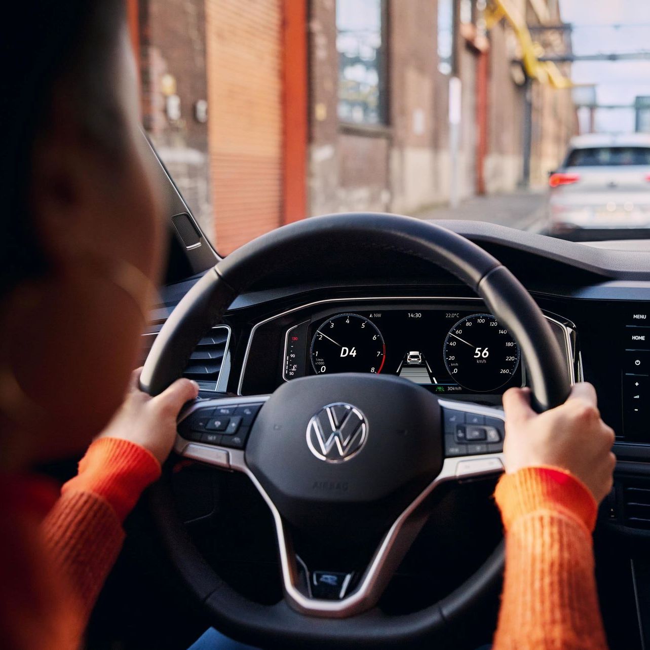 Eine Frau fährt einen VW Polo mit aktiver Navigation auf dem Display des Infotainment-Systems.