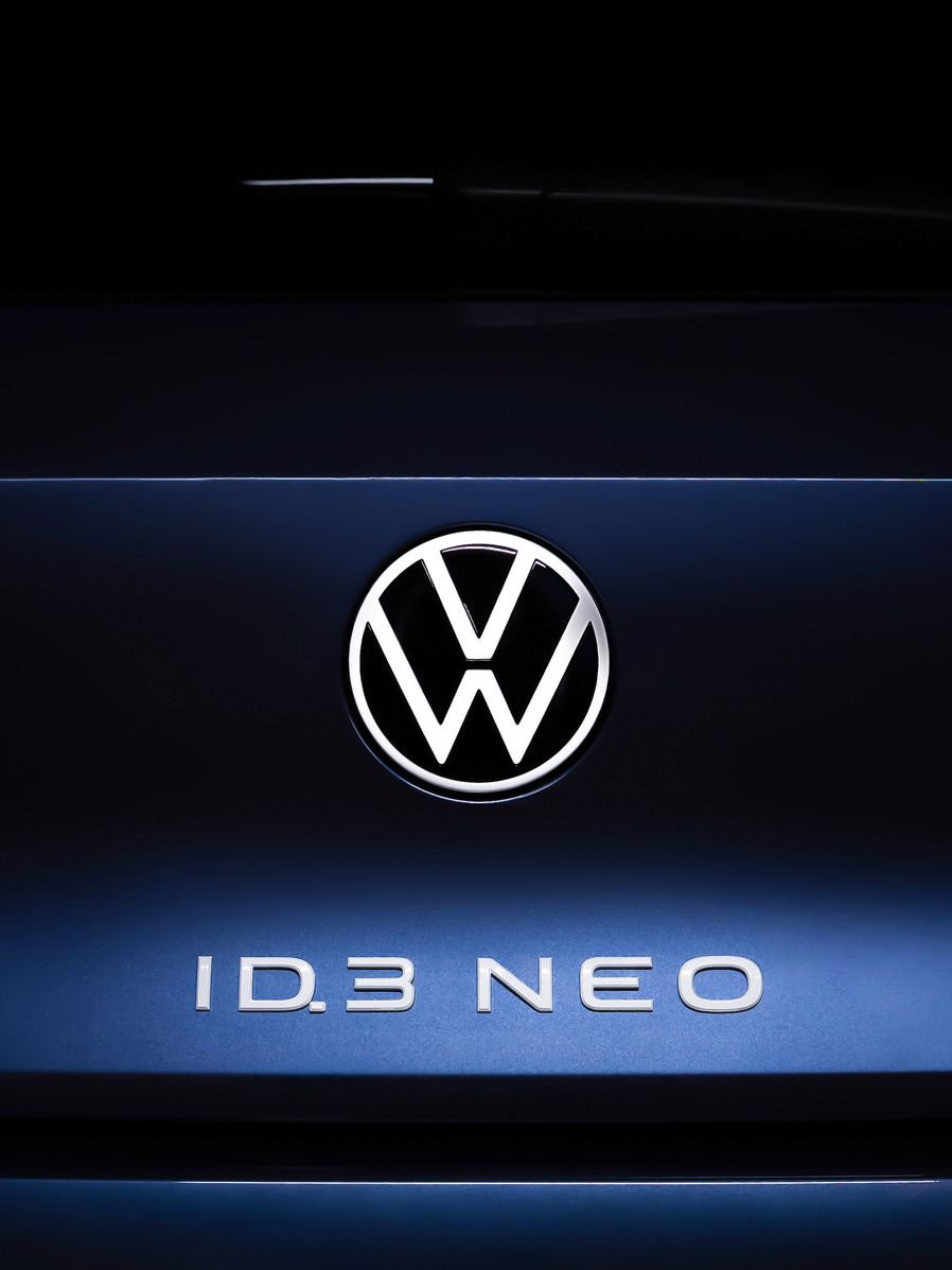Nahaufnahme des Hecks eines Volkswagen ID.3 NEO. Im Zentrum ist das Volkswagen-Logo beleuchtet, darunter steht der Schriftzug "ID.3 NEO". Die Rücklichter sind auf beiden Seiten des Logos sichtbar.