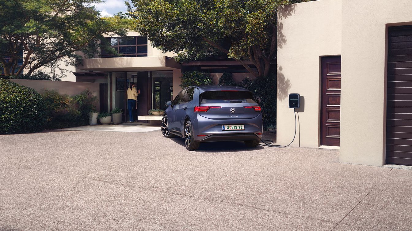 Ein blauer VW ID.3 Neo lädt an einer Wallbox vor einem Einfamilienhaus