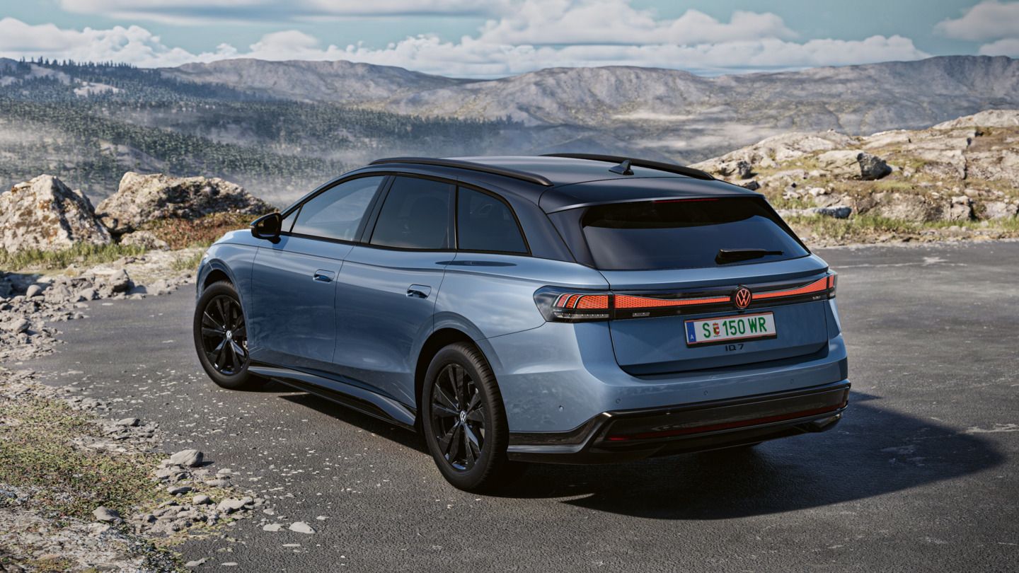 Blauer VW ID.7 Tourer in Heckansicht steht vor Felsen, im Hintergrund eine Berglandschaft.