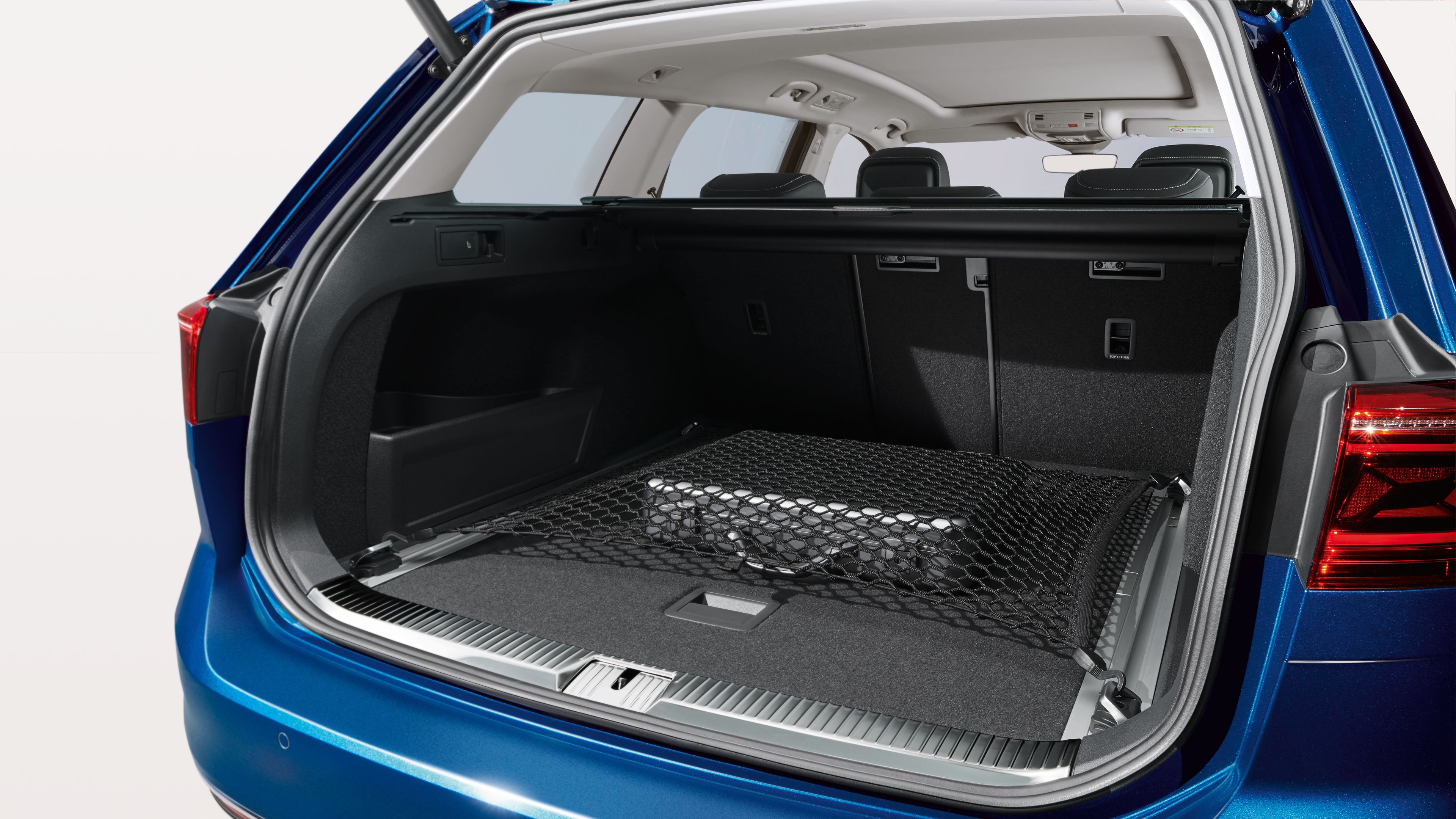 Blick in den geöffneten Kofferraum eines blauen Volkswagen, darin ist ein Koffer mit einem Volkswagen Gepäcknetz befestigt.