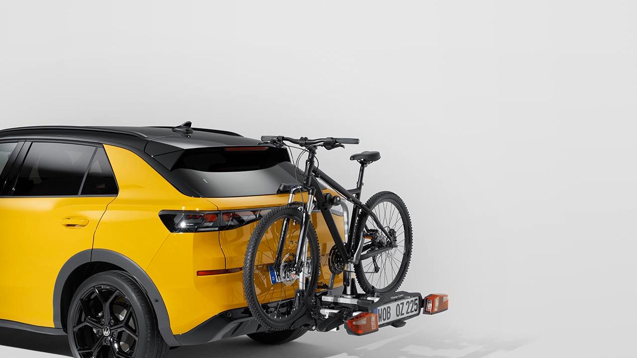 Ein Volkswagen Fahrradheckträger mit Fahrrad am Heck eines gelben Volkswagen T-Roc.