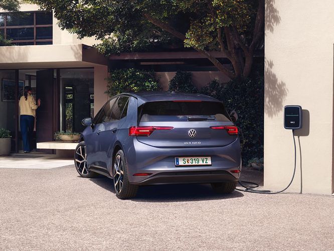 Ein blauer VW ID.3 Neo lädt an einer Wallbox vor einem Einfamilienhaus