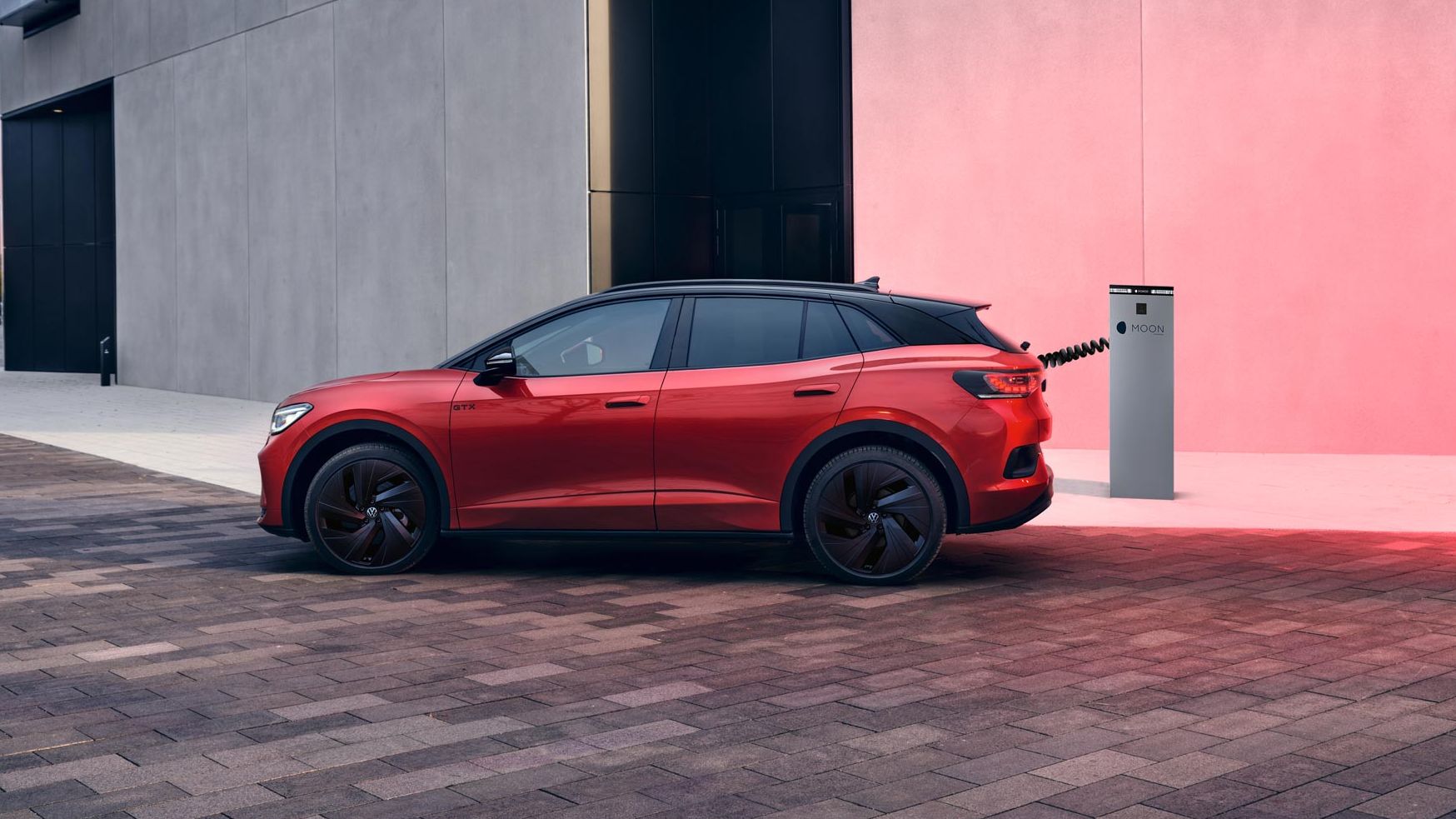 Seitenansicht eines roten VW ID.4 GTX der an Ladesäule geladen wird