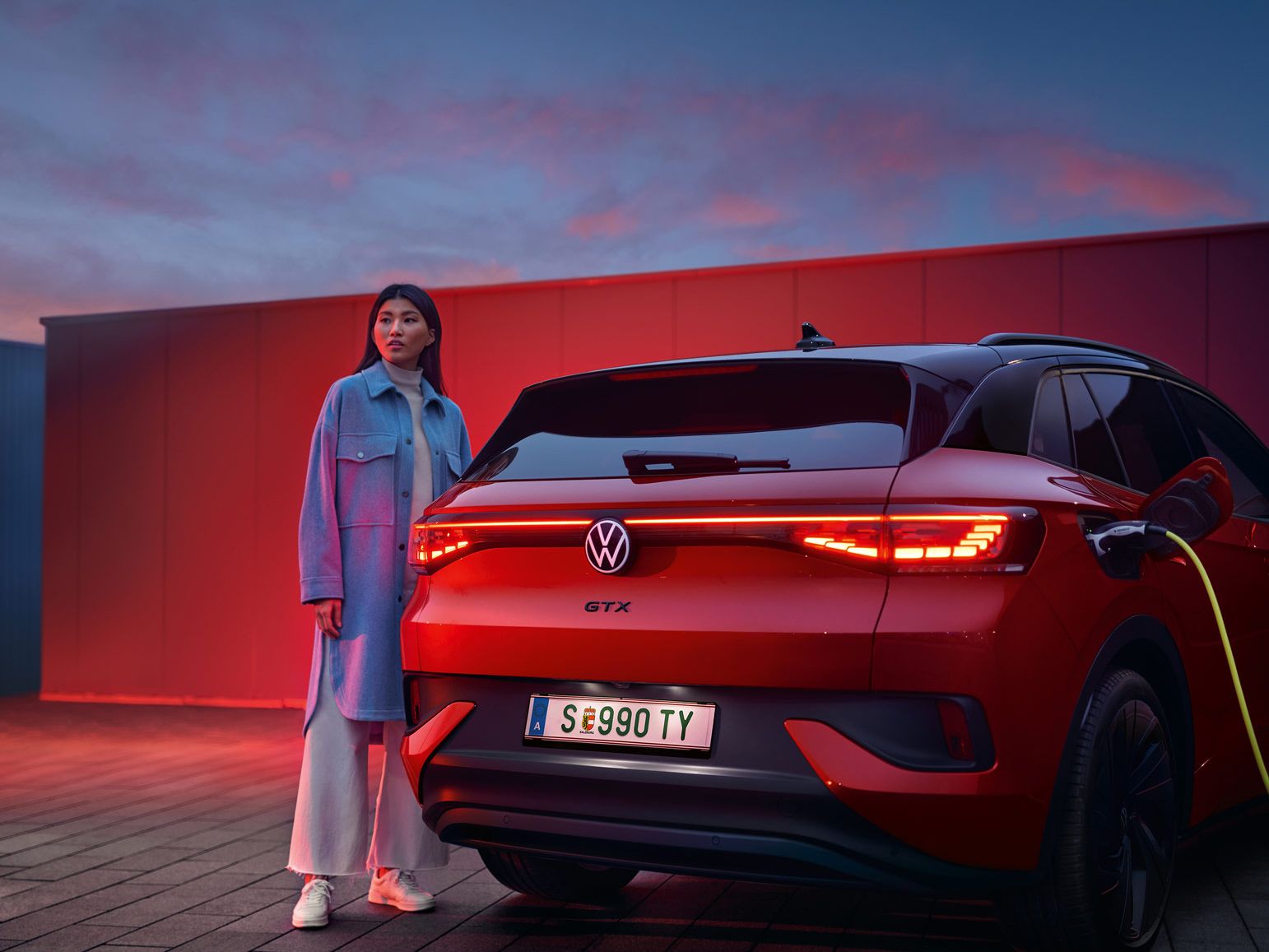 Heckansicht des VW ID.4 GTX 4MOTION, eine Frau steht daneben