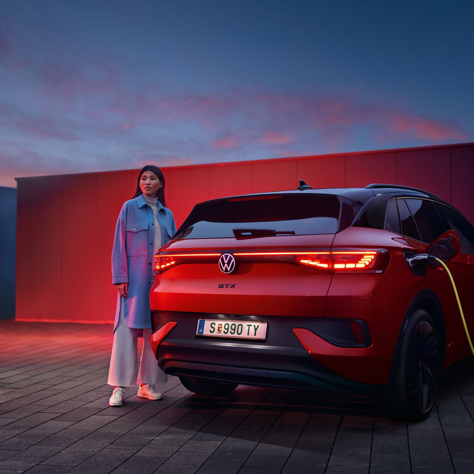 Heckansicht des VW ID.4 GTX 4MOTION, eine Frau steht daneben