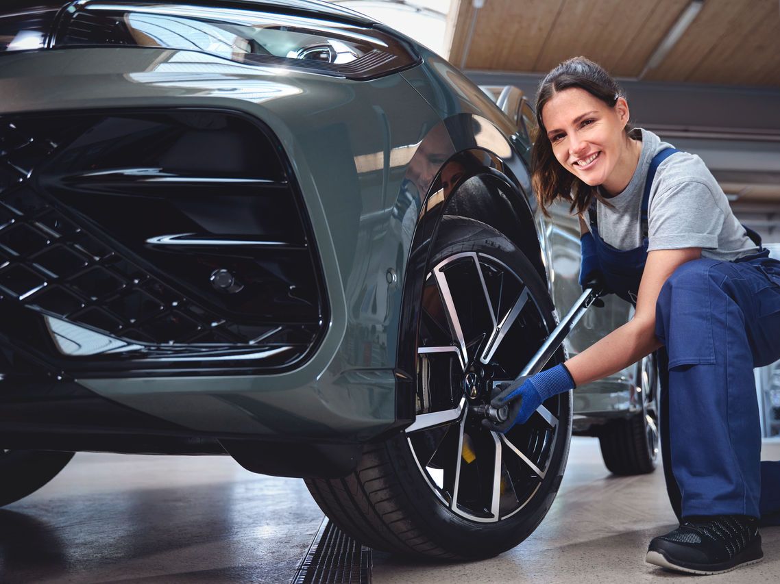 Eine Volkswagen Technikerin beim Reifenwechsel von einem Volkswagen Tiguan.