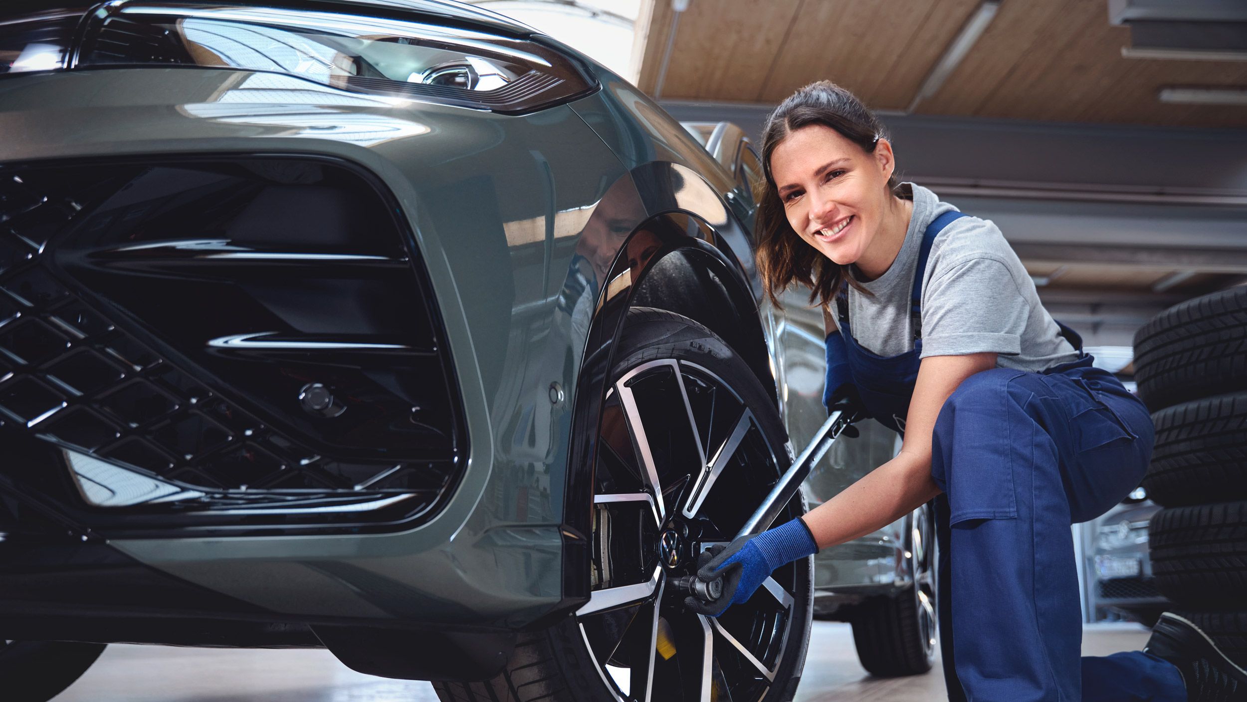 Eine Volkswagen Technikerin beim Reifenwechsel von einem Volkswagen Tiguan.