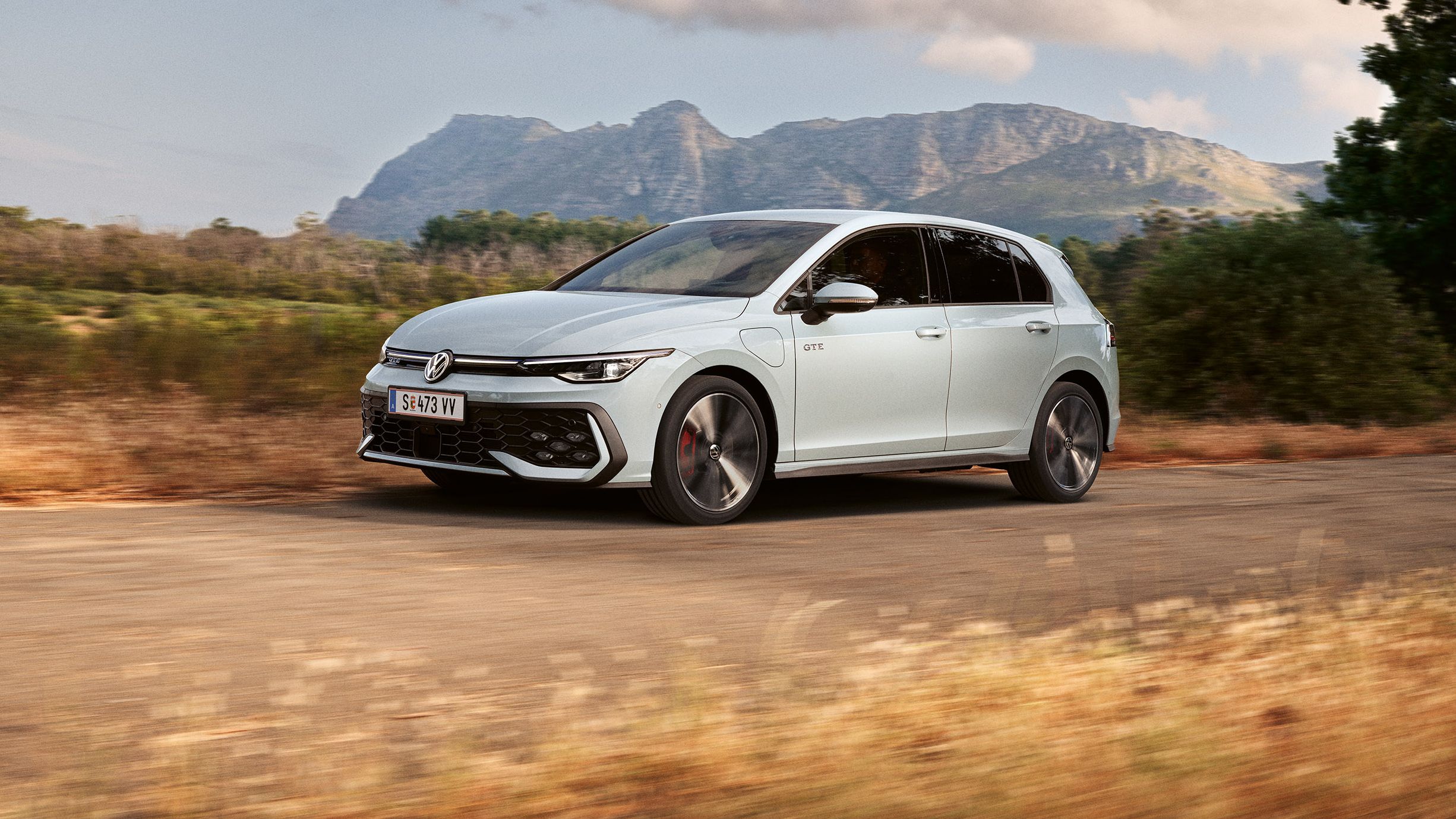 Der VW Golf GTE fährt auf einer Landstraße, im Hintergrund sieht man Berge