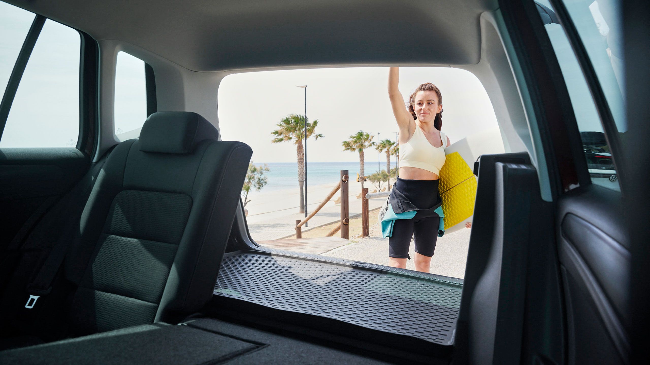 Blick durch das Heck eines Volkswagen Golf Sportsvan. Eine Frau schließt die Heckklappe.
