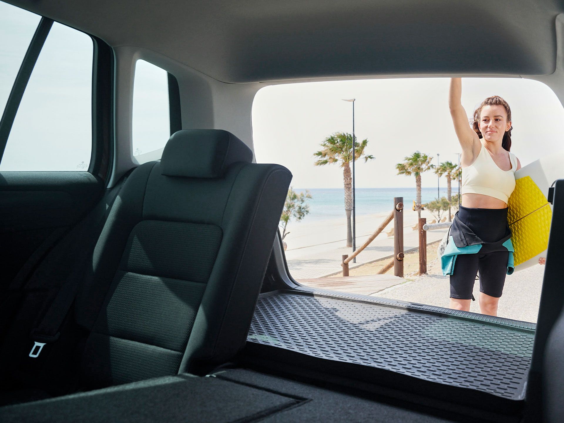 Blick durch das Heck eines Volkswagen Golf Sportsvan. Eine Frau schließt die Heckklappe.