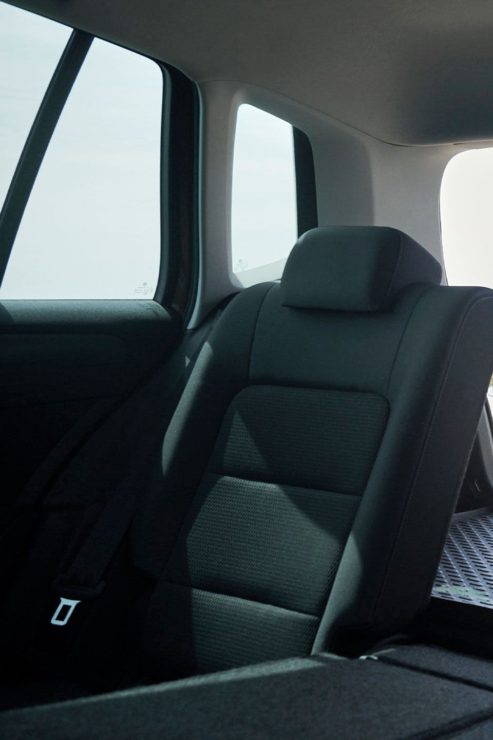Blick durch das Heck eines Volkswagen Golf Sportsvan. Eine Frau schließt die Heckklappe.