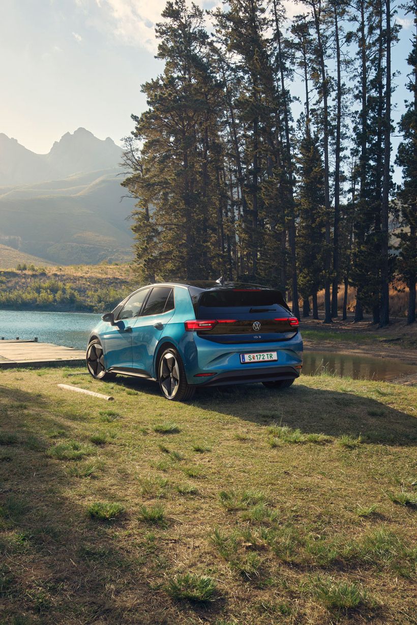 Ein blauer ID.3 steht am Ufer eines Sees, umgeben von hohen Bäumen.