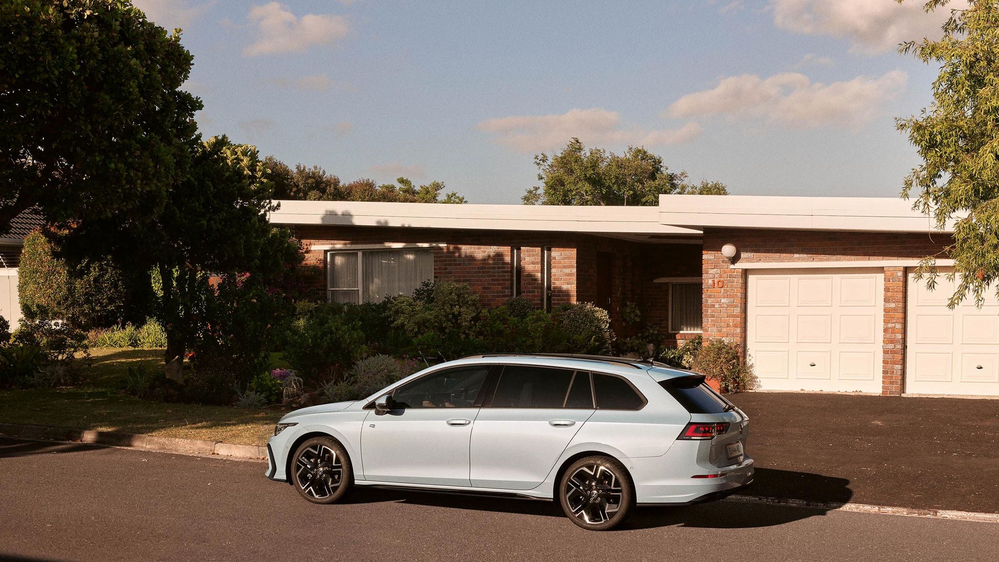 Seitenansicht eines VW Golf Variant in der Farbe Ice Blue Metallic geparkt vor Einfamilienhaus