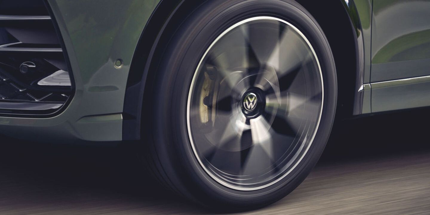 Eine Detailaufnahme des linken Vorderrads eines grünen VW Tiguan.