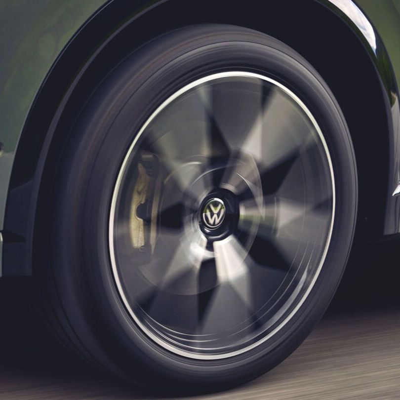 Eine Detailaufnahme des linken Vorderrads eines grünen VW Tiguan.