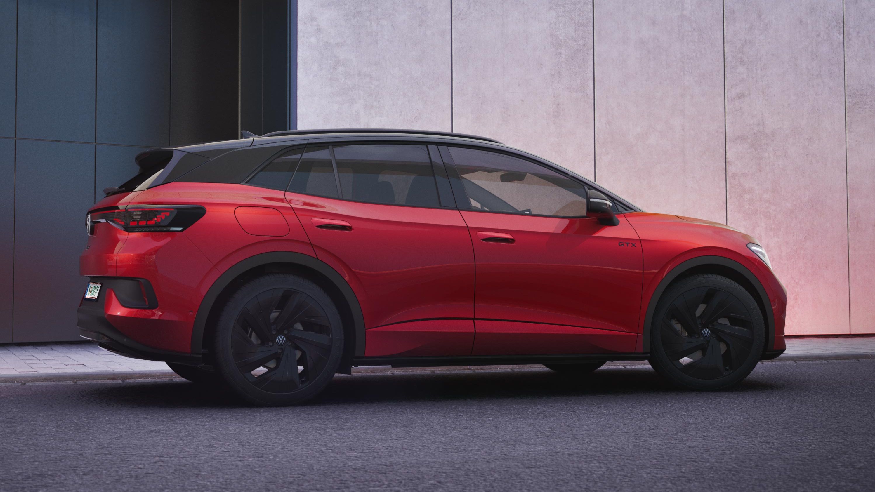 Ein roter VW ID.4 GTX parkt seitlich vor einer modernen Hauswand.