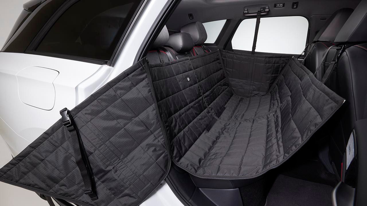 Blick auf den Rücksitz eines weißen Volkswagen mit ausgebreiteter Fondschutzdecke. Reißverschluss auf einer Seite geöffnet.