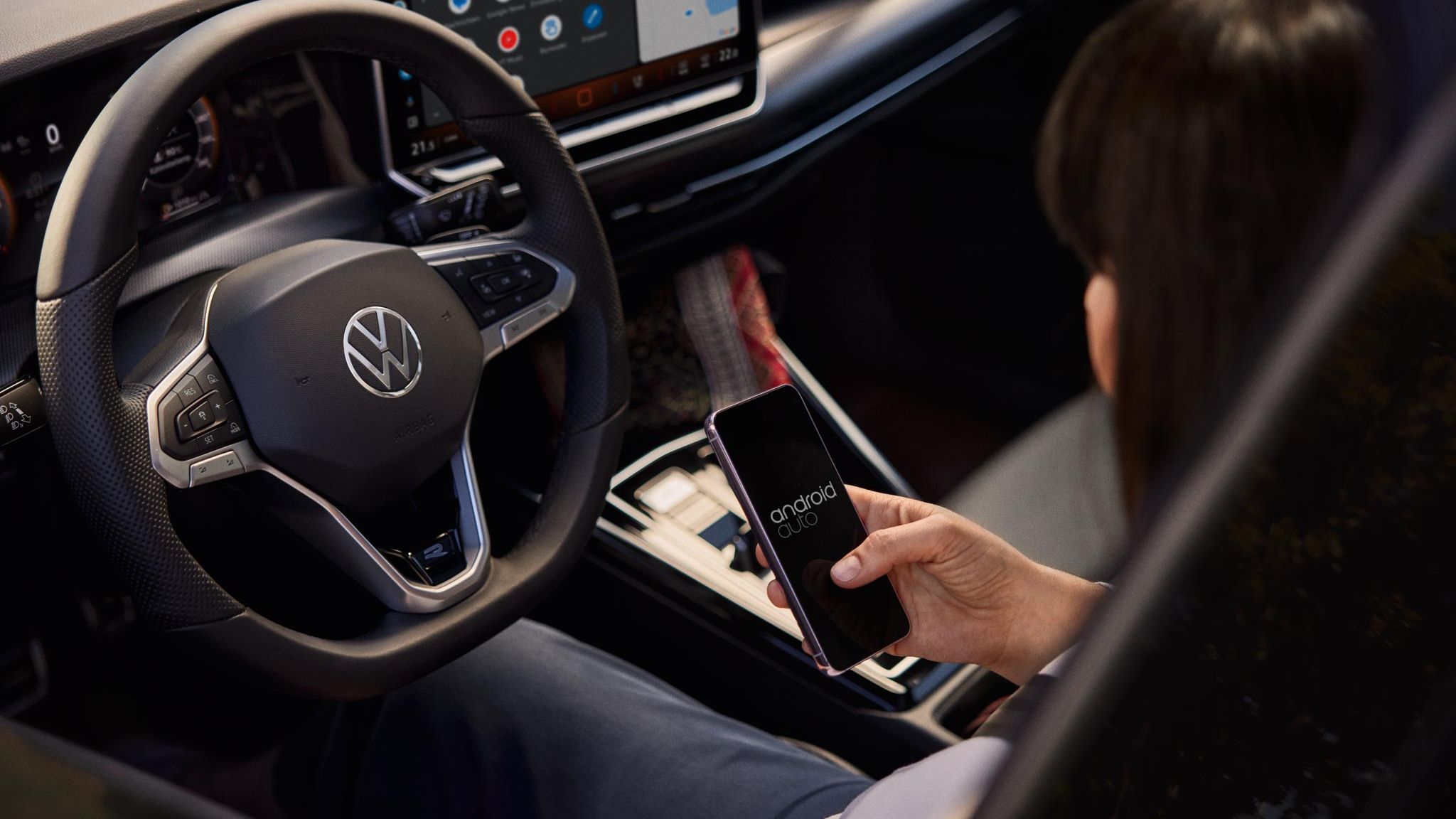 Frau sitzt im VW Golf Variant und nutzt Wireless App-Connect mit ihrem Smartphone