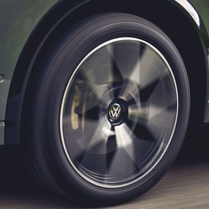 Eine Detailaufnahme des linken Vorderrads eines grünen VW Tiguan.