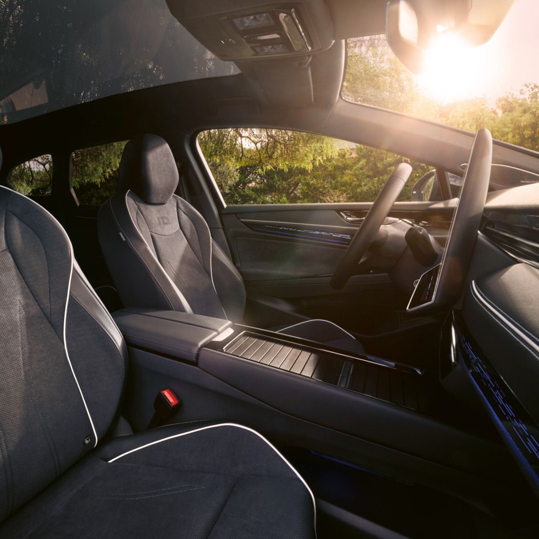 Vordersitze des ID.7 Tourer, Interieur mit Ambientebeleuchtung und Panoramadach. 