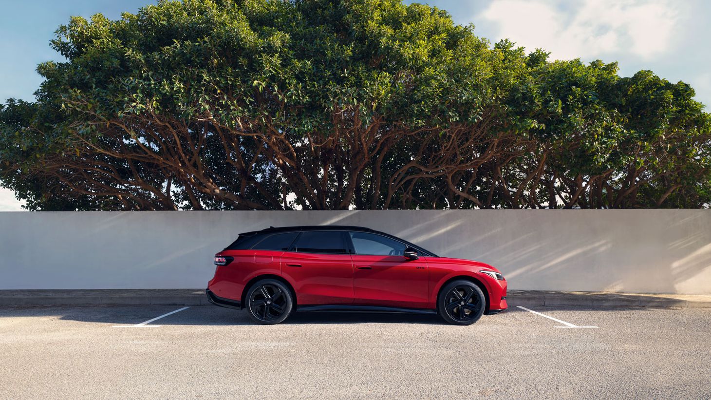 Der VW ID.7 Tourer GTX parkt vor einem Baum (Seitenansicht)