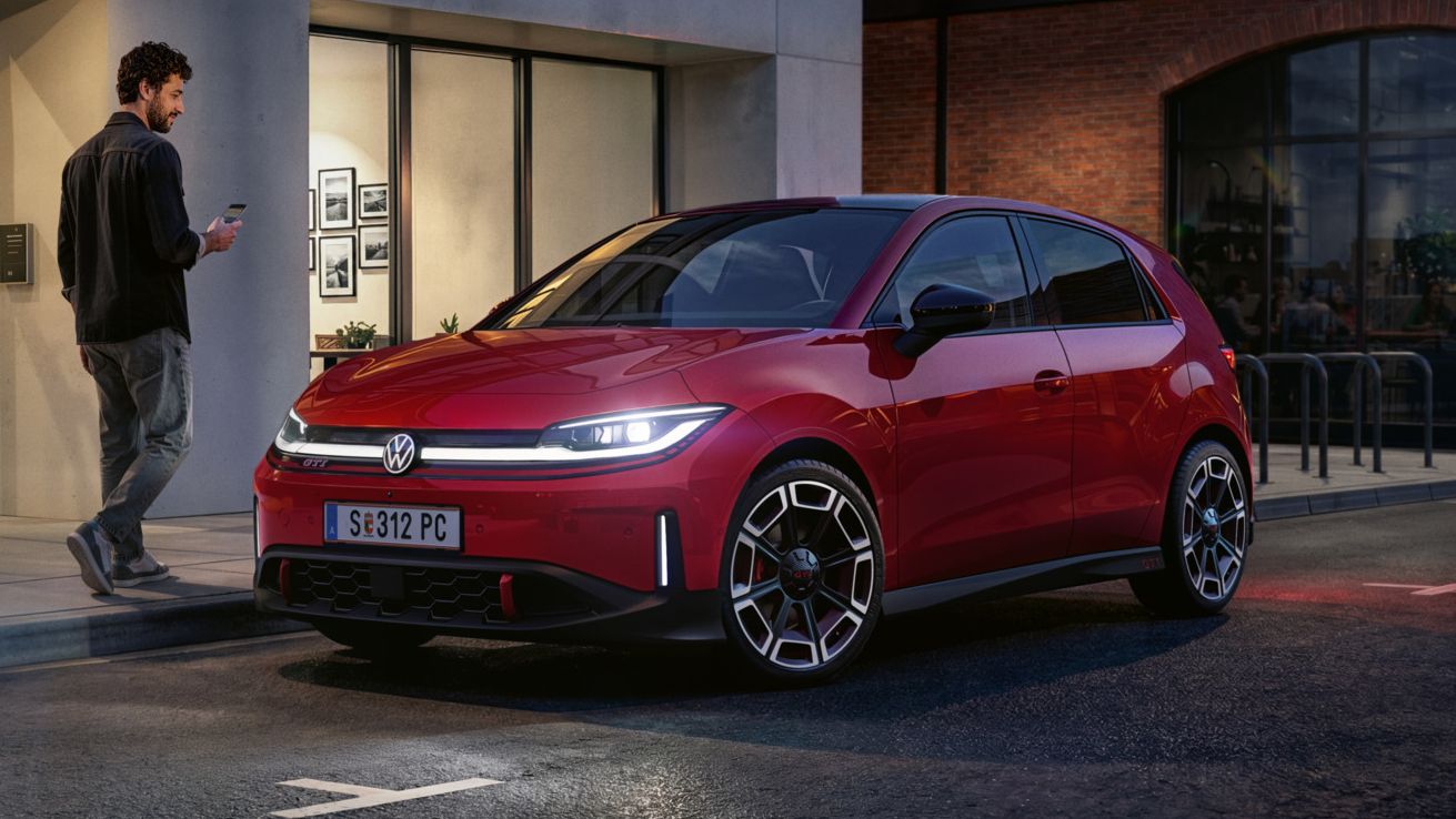 Eine Person geht an einem roten VW ID. Polo GTI vorbei, der vor einem modernen Gebäude parkt.