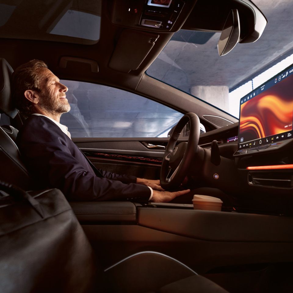 Ein Mann sitzt entspannt im VW ID.7, sichtbar sind Lenkrad und Infotainment-Display.