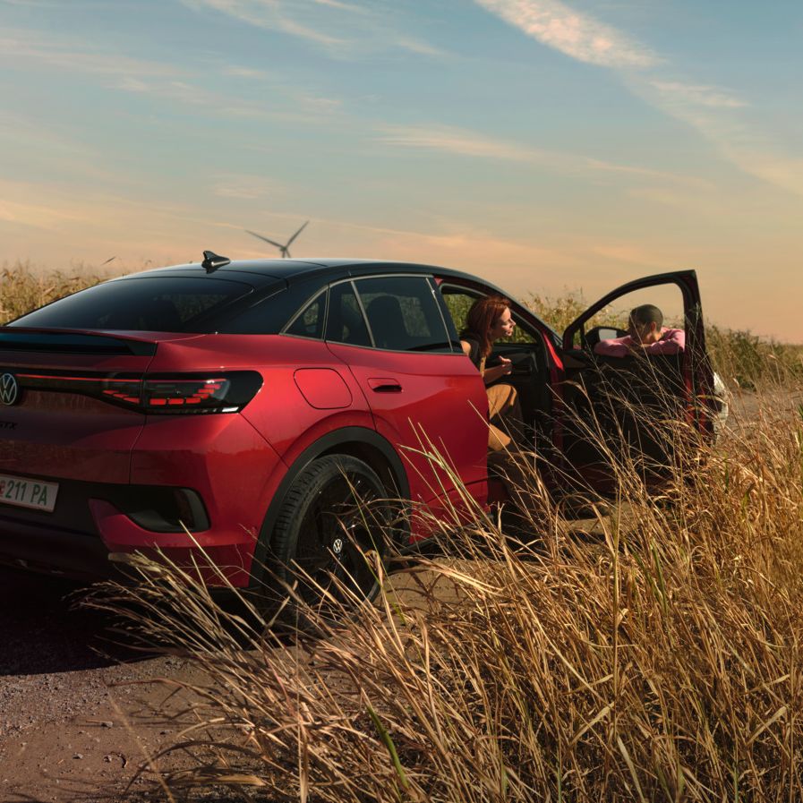 Zwei Personen unterhalten sich neben einem roten ID.5 GTX auf einer Landstraße