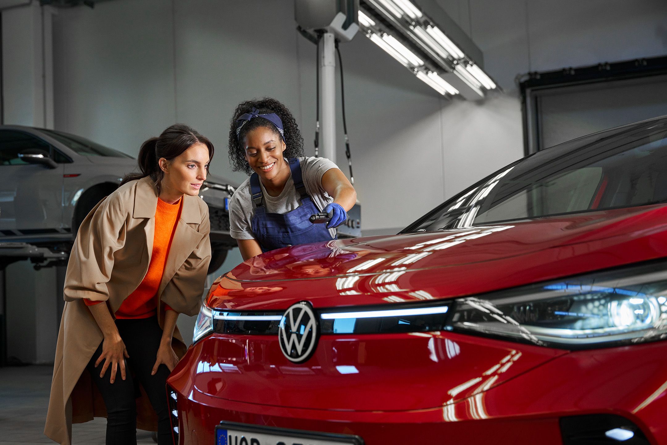 Eine Volkswagen Technikerin erklärt einer Kundin die Lackreparatur