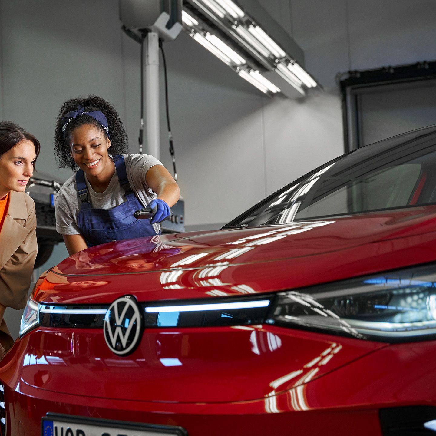 Eine Volkswagen Technikerin erklärt einer Kundin die Lackreparatur