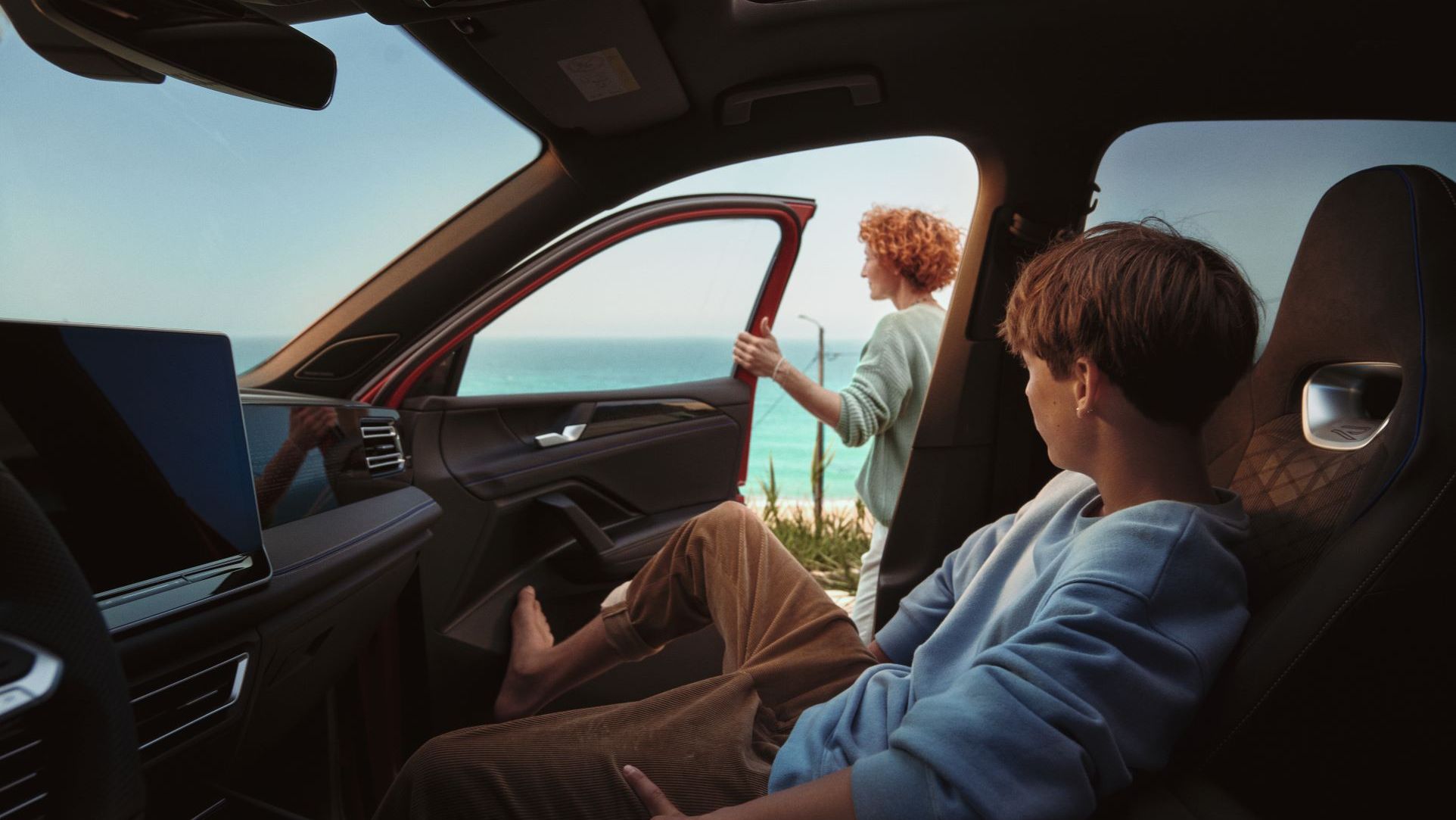 Kind sitzt im Tiguan und schaut zu seiner Mutter, die vor geöffneter Türe steht