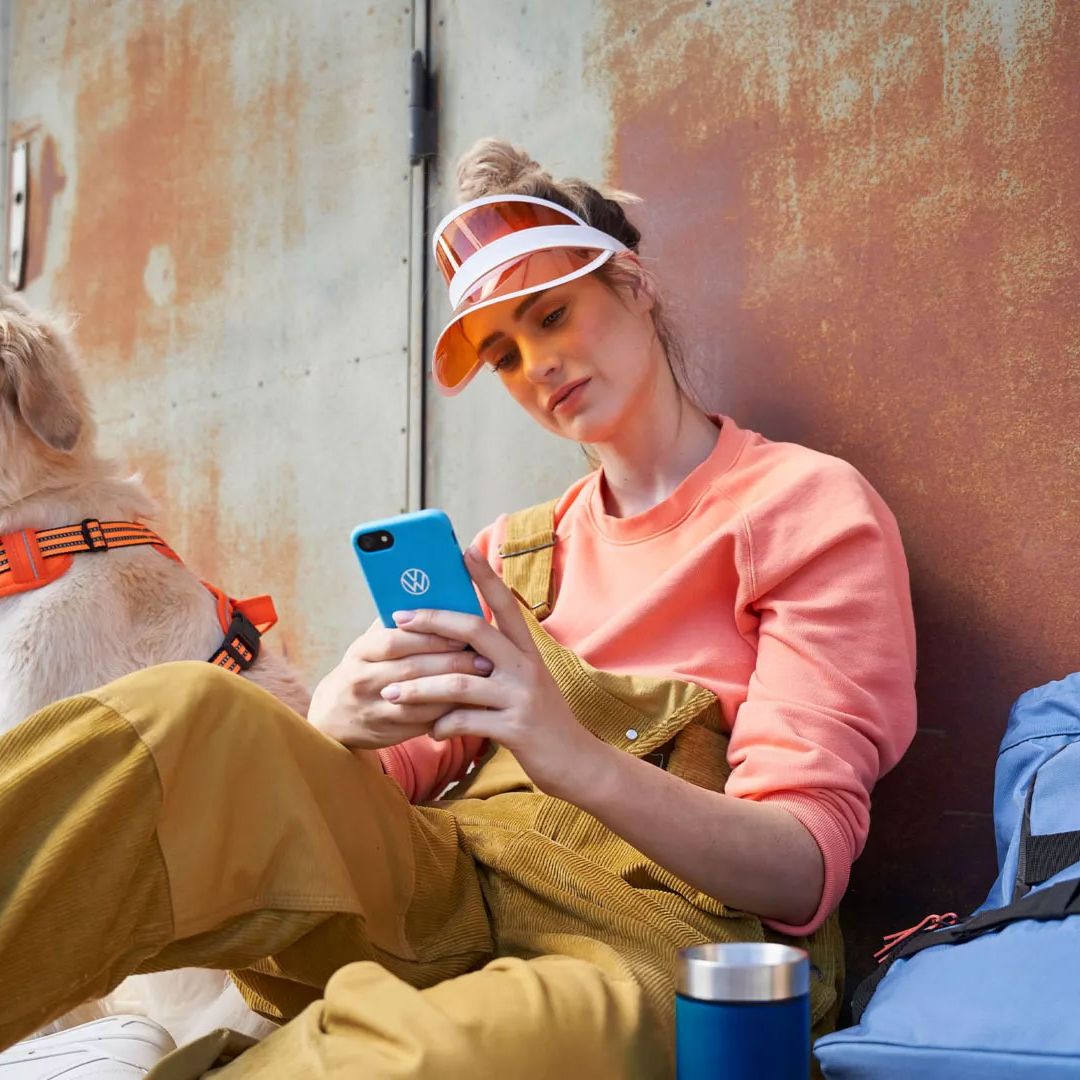 Eine Frau blickt auf ihr Smartphone, ein Hund ist bei ihr