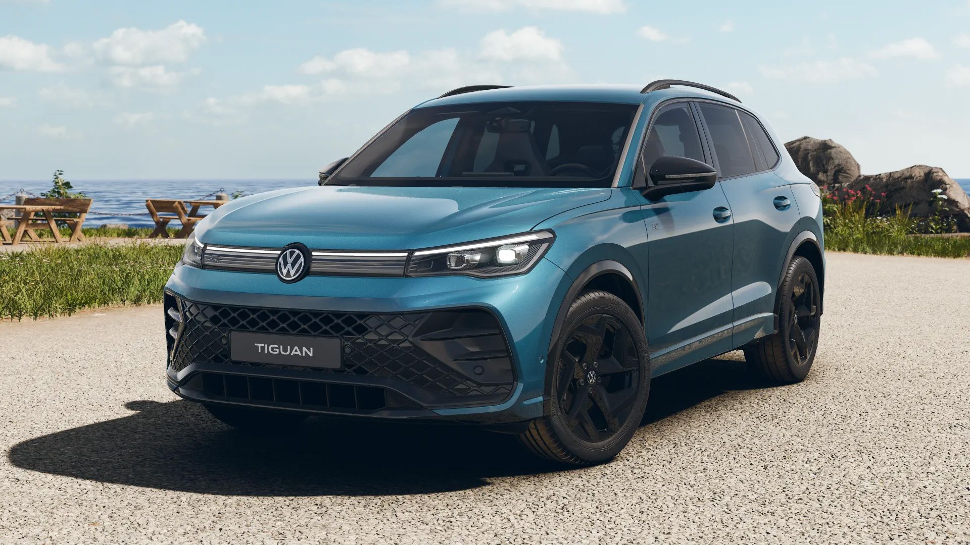 VW Tiguan R-Line in Nightshade Blue Metallic mit schwarzen Designelementen an einer Küstenpromenade.