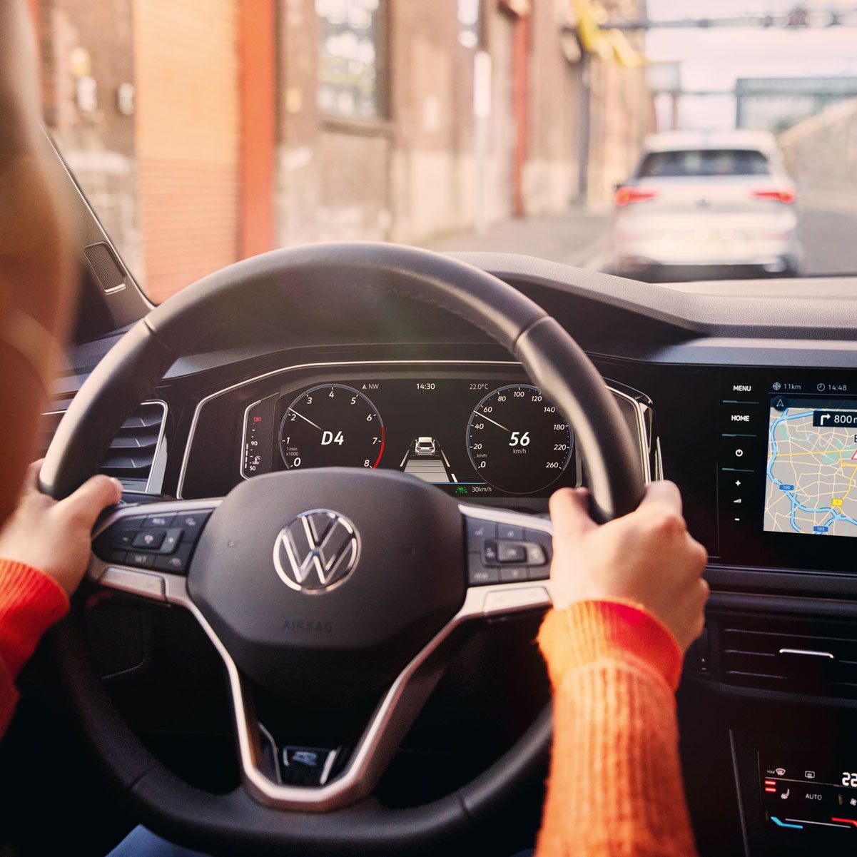 Eine Frau fährt einen VW Polo mit aktiver Navigation auf dem Display des Infotainment-Systems.