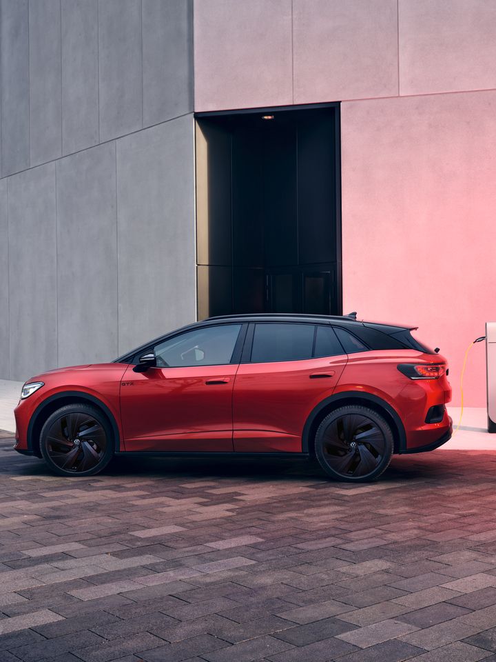 Seitenansicht eines roten VW ID.4 GTX der an Ladesäule geladen wird