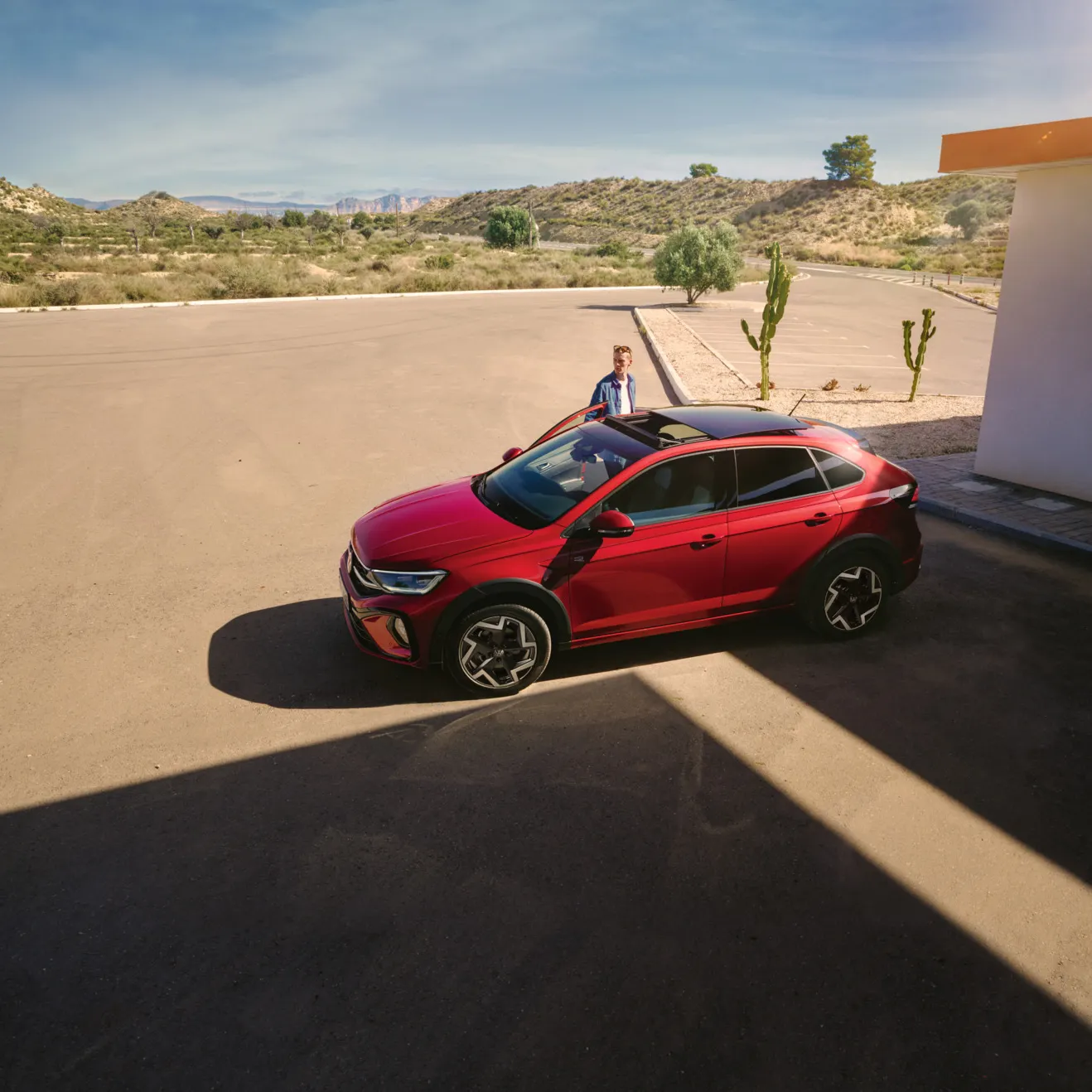 Seitenansicht eines roten VW Taigo R-Line, Mann öffnet Beifahrertür
