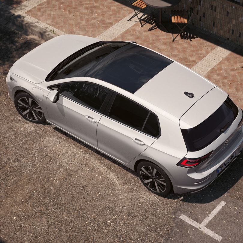 Ein weißer VW Golf eHybrid mit Panoramadach aus der Vogelperspektive, von oben