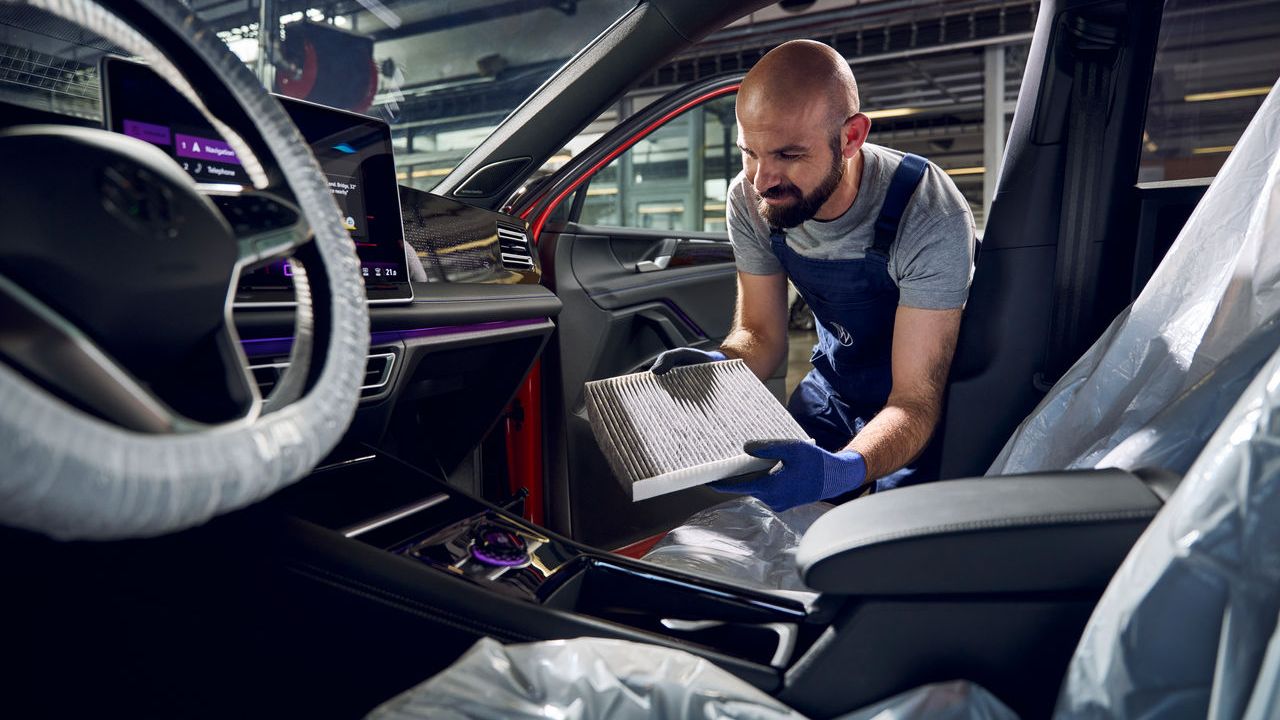 Ein Volkswagen Techniker tauscht einen Filter der Klimaanlage eines Volkswagen.